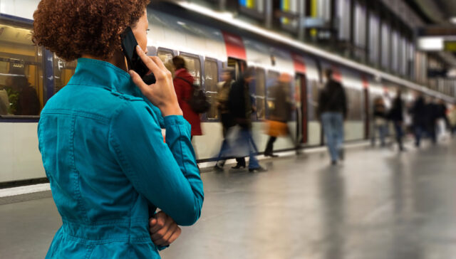 Woman on cell phone in front of a subway train.