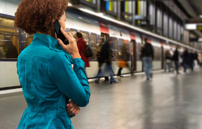 Woman on cell phone in front of a subway train.
