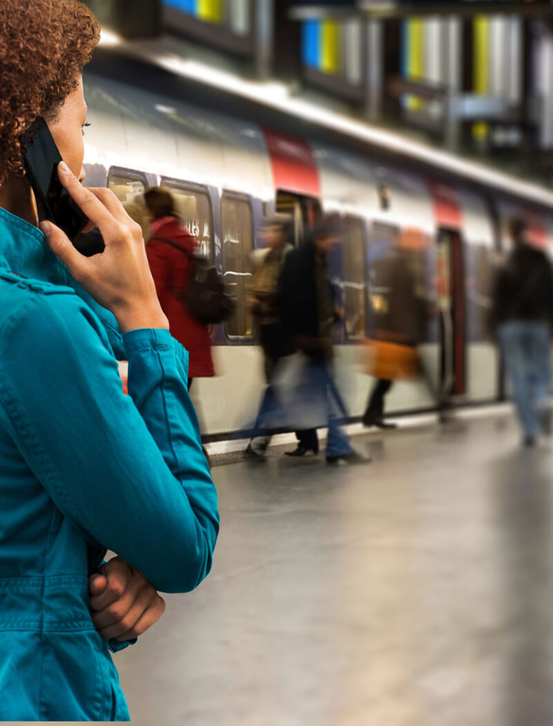 Woman on cell phone in front of a subway train.