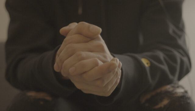 Single individual clasping their hands together