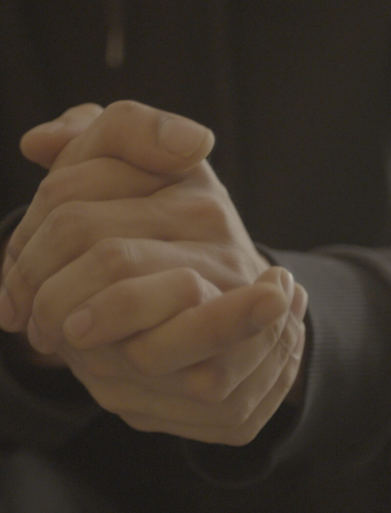 Single individual clasping their hands together