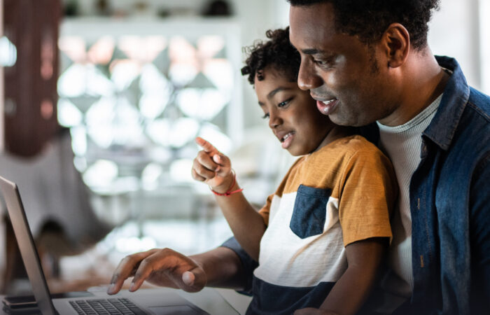 Man with child on his lap works on laptop