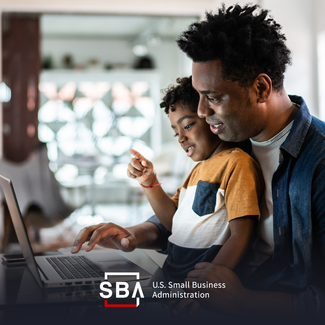 Man with child on his lap works on laptop