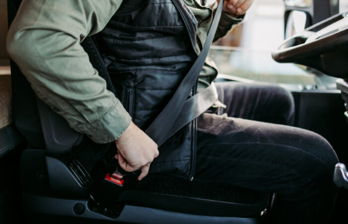 Man buckling his seat belt as he sits in his commercial truck