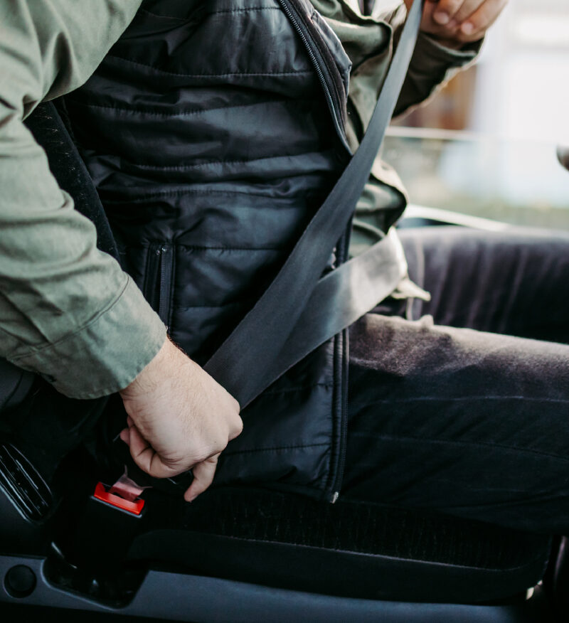 Man buckling his seat belt as he sits in his commercial truck