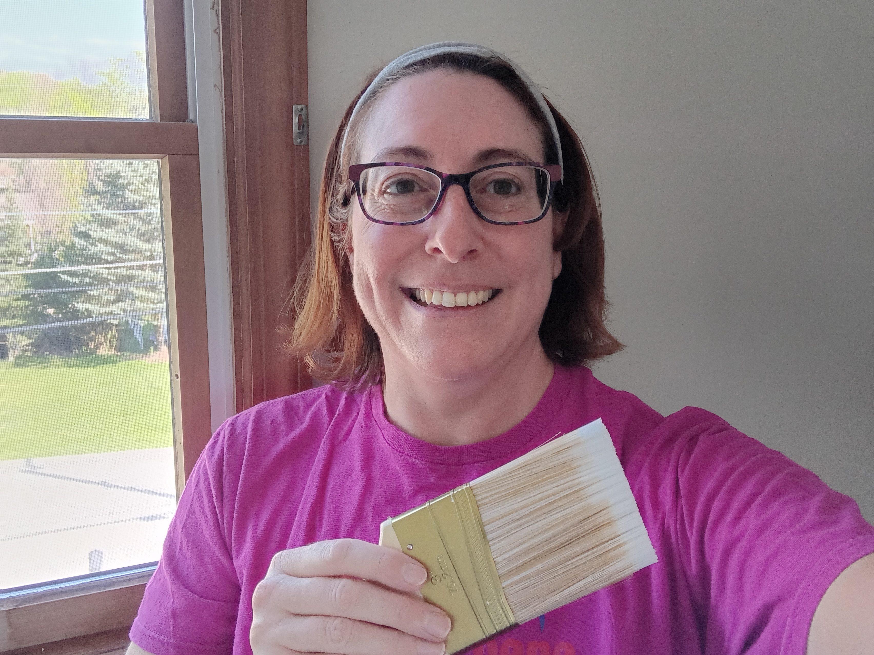 Woman smiling while holding a paintbrush.