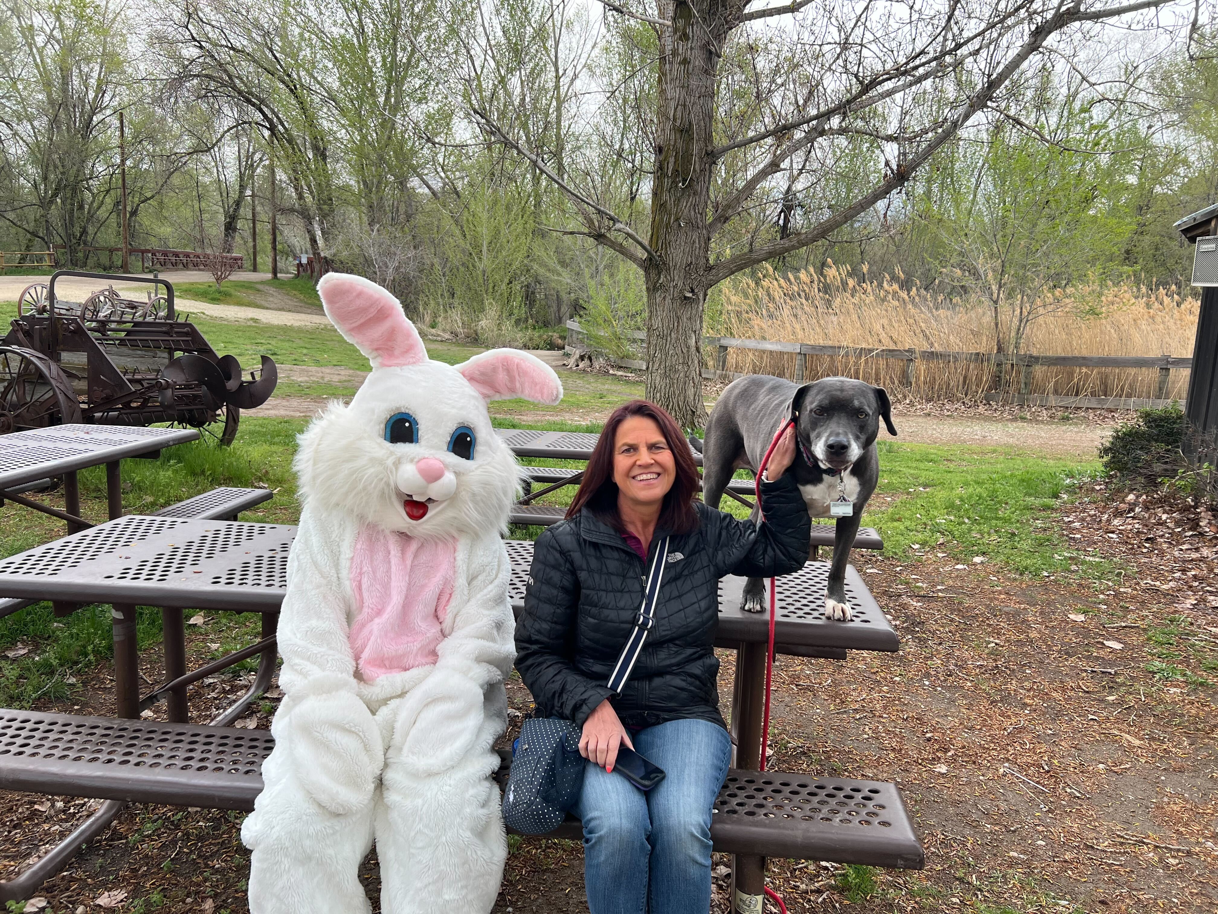 Person in a bunny suit posing with a woman and a dog. 